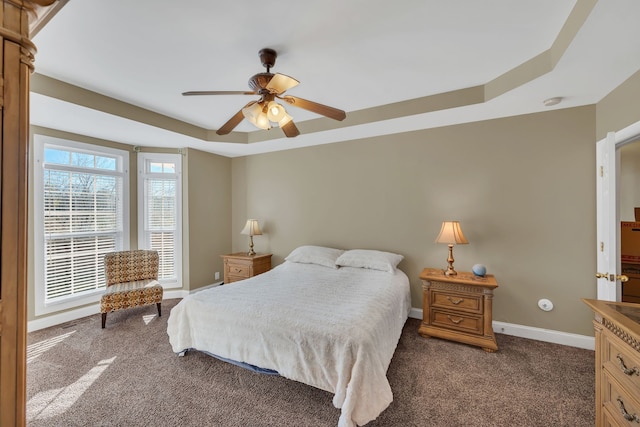 bedroom featuring dark carpet, a raised ceiling, and ceiling fan