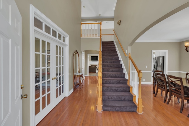 foyer featuring crown molding, french doors, wood-type flooring, and a high ceiling