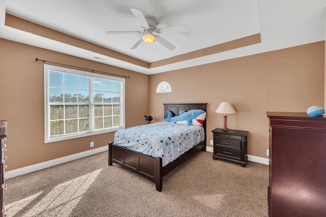 bedroom with light carpet, a raised ceiling, and ceiling fan