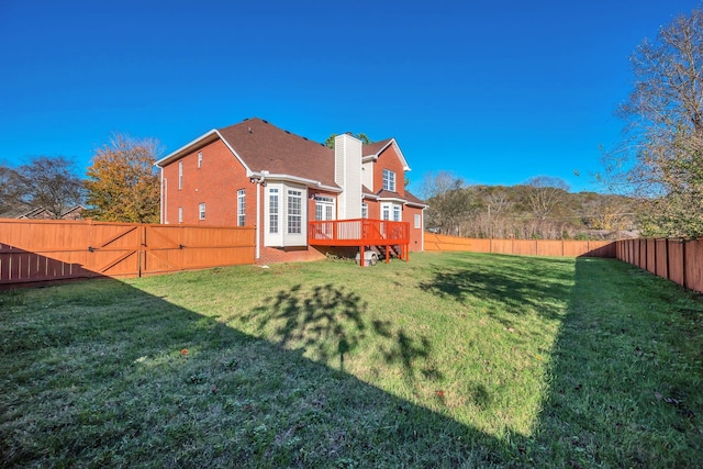 back of house featuring a lawn and a wooden deck