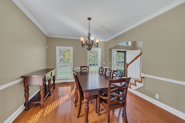 dining room with wood-type flooring, crown molding, and a wealth of natural light