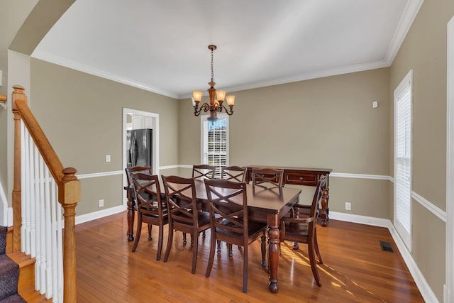 dining space featuring crown molding, an inviting chandelier, and hardwood / wood-style flooring