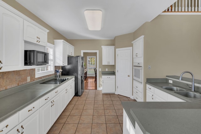 kitchen featuring white cabinets, light tile patterned floors, sink, and black appliances