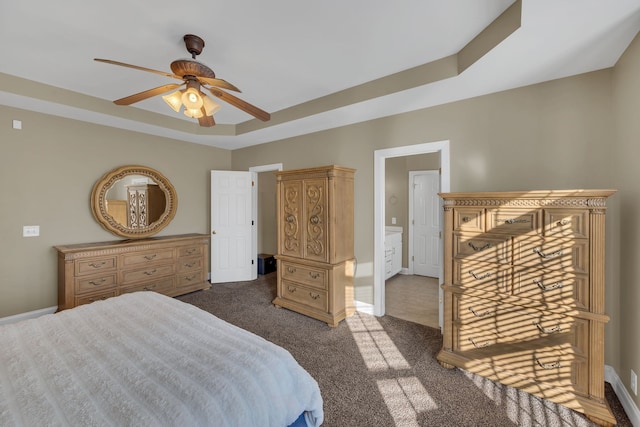 bedroom featuring a raised ceiling, dark carpet, and ceiling fan