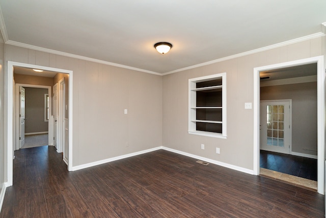 empty room featuring built in features, dark wood-type flooring, and ornamental molding