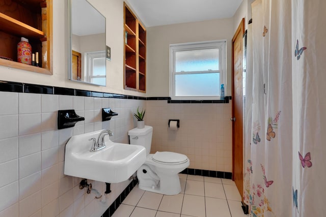 full bathroom featuring tile patterned floors, wainscoting, toilet, and tile walls