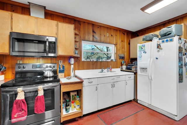 kitchen featuring a sink, light countertops, wood walls, and stainless steel appliances