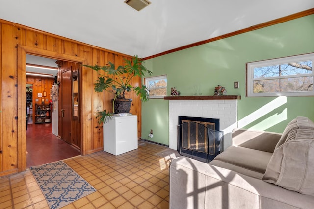 living room with visible vents, wood walls, a brick fireplace, and plenty of natural light