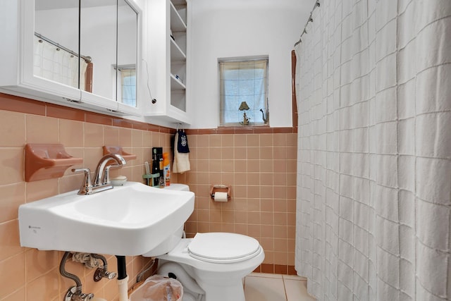 full bathroom with a sink, a shower with curtain, toilet, and tile walls