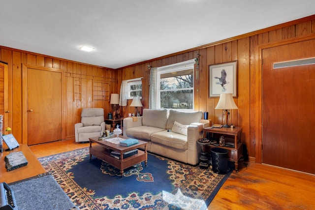 living area with wood finished floors, ornamental molding, and wood walls