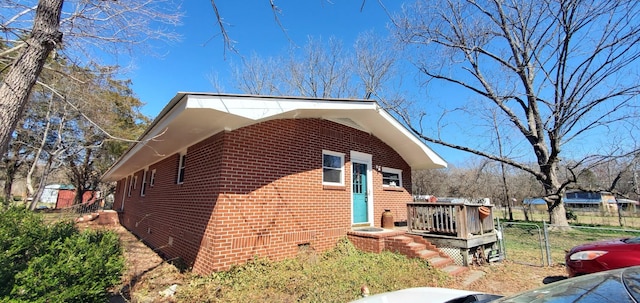 view of property exterior featuring crawl space, brick siding, and fence