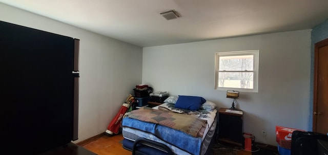 bedroom with visible vents, freestanding refrigerator, and wood finished floors