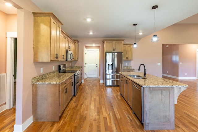 kitchen with a center island with sink, sink, hanging light fixtures, light hardwood / wood-style flooring, and stainless steel appliances