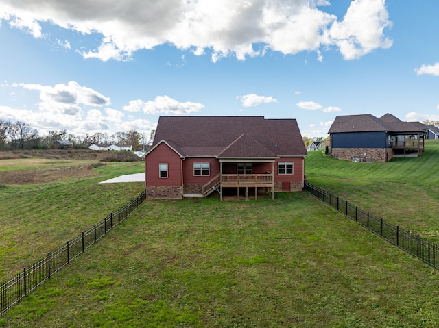 back of property with a rural view, a wooden deck, and a lawn