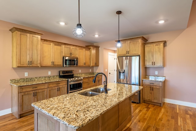 kitchen with light hardwood / wood-style floors, sink, stainless steel appliances, and hanging light fixtures