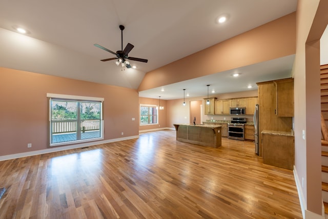 unfurnished living room with ceiling fan with notable chandelier, light wood-type flooring, and lofted ceiling