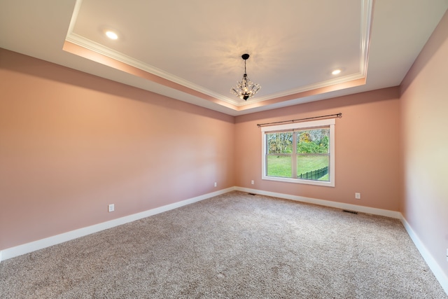 carpeted spare room featuring a chandelier, a tray ceiling, and crown molding