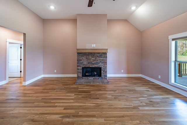 unfurnished living room featuring vaulted ceiling, light hardwood / wood-style flooring, ceiling fan, and a stone fireplace