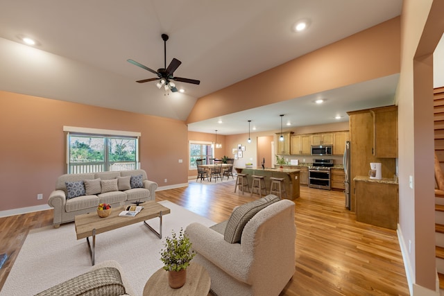 living room featuring ceiling fan, lofted ceiling, and light wood-type flooring