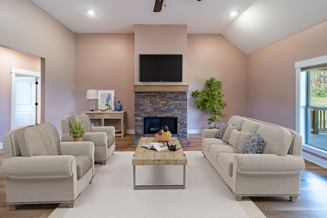 living room featuring ceiling fan, a fireplace, lofted ceiling, and light wood-type flooring