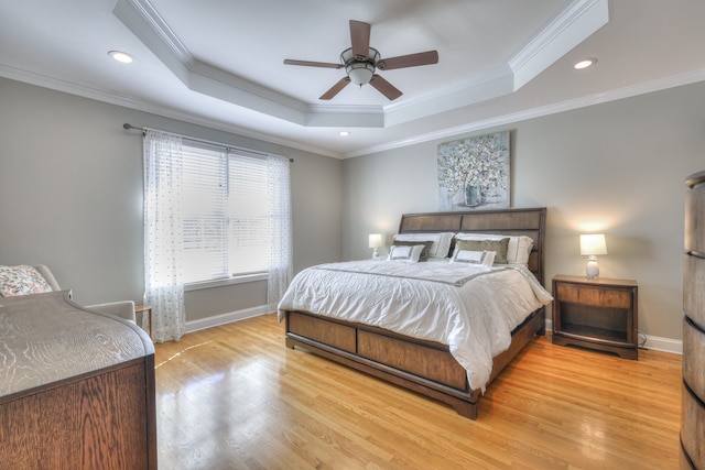 bedroom featuring a raised ceiling, crown molding, ceiling fan, and light wood-type flooring