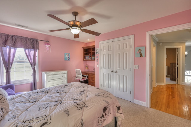 bedroom featuring light wood-type flooring, ceiling fan, and built in desk