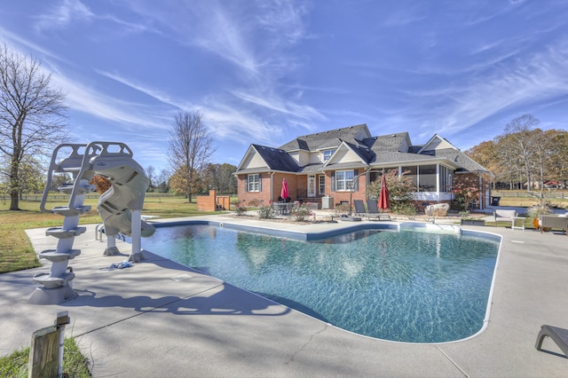 view of pool with a patio, a sunroom, and a water slide