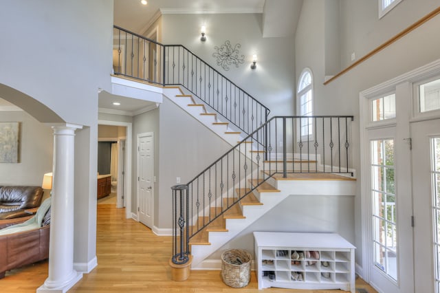 entryway with a high ceiling, decorative columns, light hardwood / wood-style flooring, and crown molding