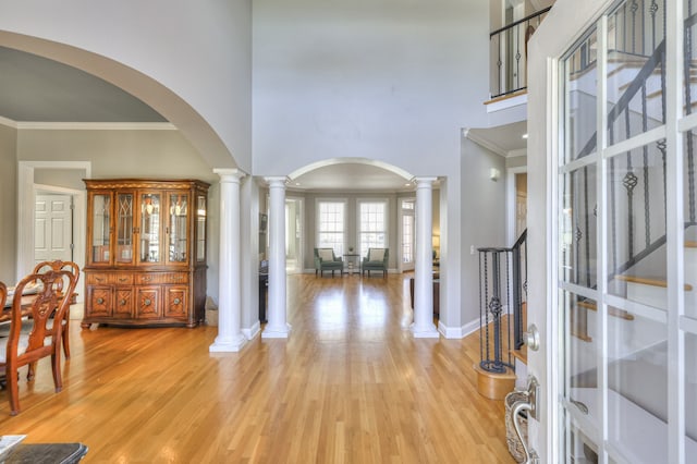 entryway featuring light hardwood / wood-style floors, a high ceiling, and ornamental molding