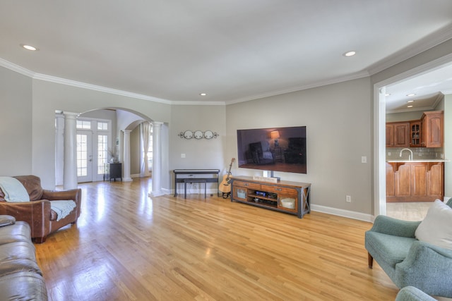 living room with light wood-type flooring, decorative columns, and ornamental molding