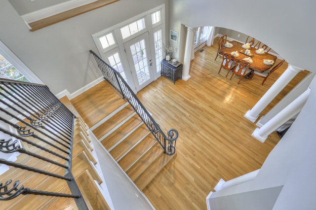 stairway with decorative columns, hardwood / wood-style floors, and a towering ceiling