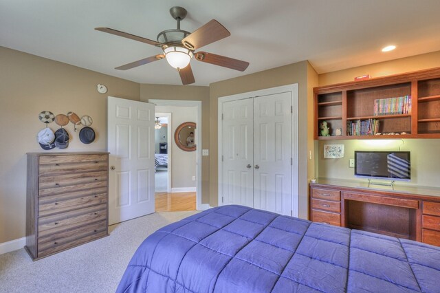 carpeted bedroom featuring ceiling fan, built in desk, and a closet