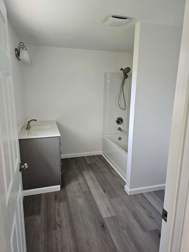 bathroom featuring hardwood / wood-style flooring, vanity, and bathing tub / shower combination