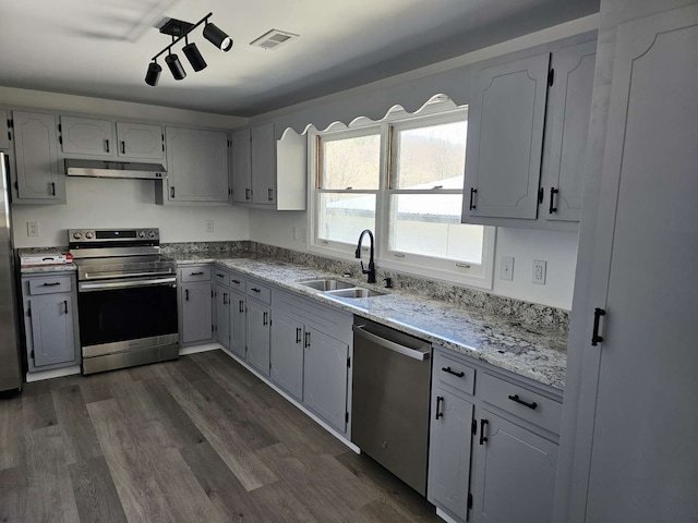 kitchen with stainless steel appliances, light stone counters, dark hardwood / wood-style floors, and sink