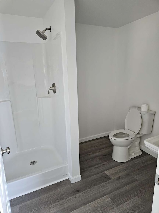 bathroom with hardwood / wood-style flooring, toilet, and walk in shower