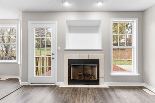 doorway to outside with a fireplace, wood-type flooring, and a textured ceiling