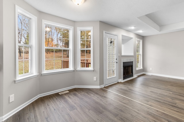 unfurnished living room with a fireplace, a textured ceiling, and dark hardwood / wood-style flooring