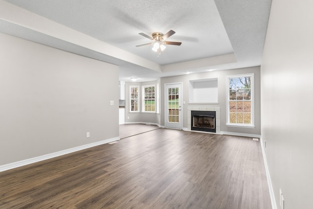 unfurnished living room featuring a fireplace, hardwood / wood-style floors, a textured ceiling, and a wealth of natural light