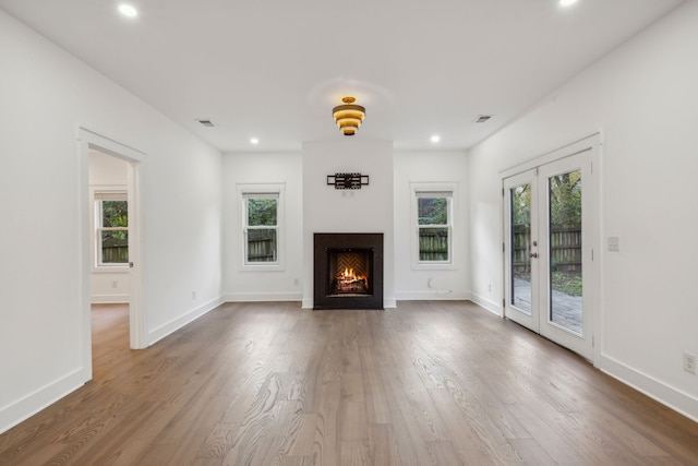 unfurnished living room with hardwood / wood-style floors, french doors, and a healthy amount of sunlight