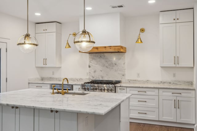 kitchen featuring stainless steel stove, white cabinetry, and sink