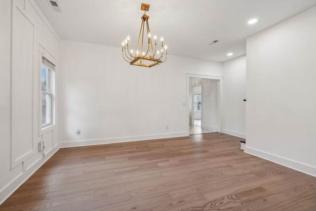 spare room featuring hardwood / wood-style floors and an inviting chandelier