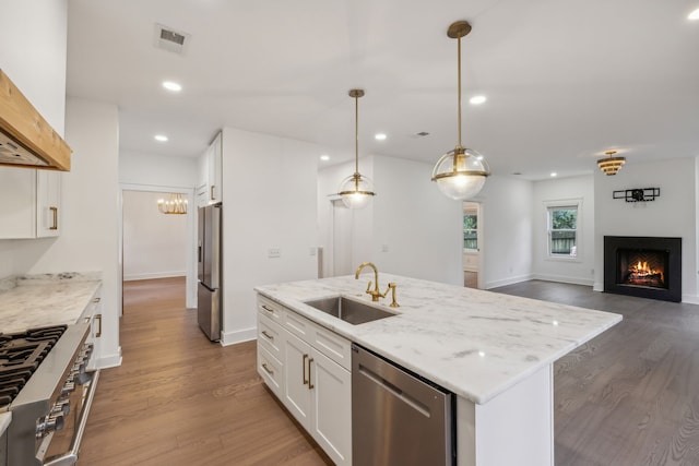 kitchen with sink, decorative light fixtures, a kitchen island with sink, white cabinets, and appliances with stainless steel finishes