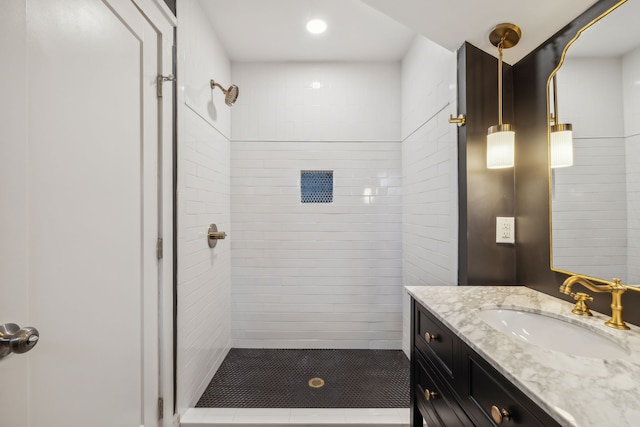 bathroom featuring tiled shower and vanity