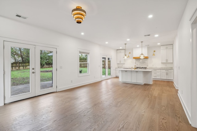 unfurnished living room with french doors, light hardwood / wood-style flooring, and a healthy amount of sunlight