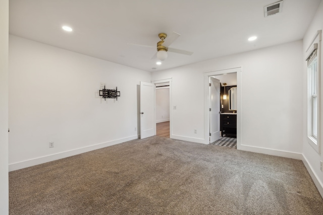 unfurnished bedroom with carpet flooring, ceiling fan, connected bathroom, and multiple windows