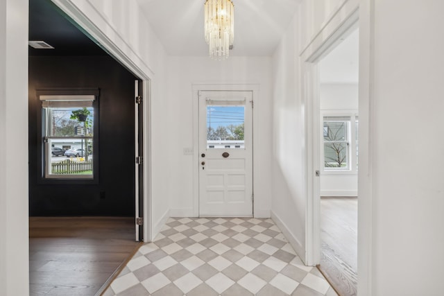 interior space with a chandelier, light wood-type flooring, and a healthy amount of sunlight