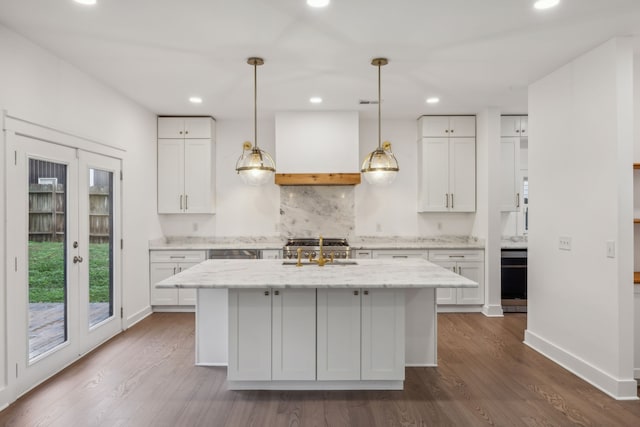 kitchen with white cabinets, light stone counters, dark hardwood / wood-style flooring, and a kitchen island with sink