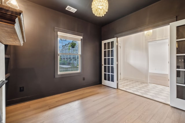 spare room featuring a chandelier and light hardwood / wood-style flooring