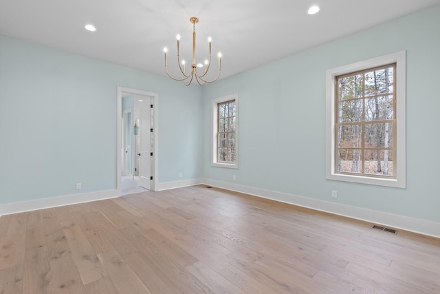 empty room with a chandelier, light wood-style flooring, baseboards, and recessed lighting