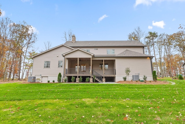back of house featuring a chimney, a lawn, a ceiling fan, and stairs